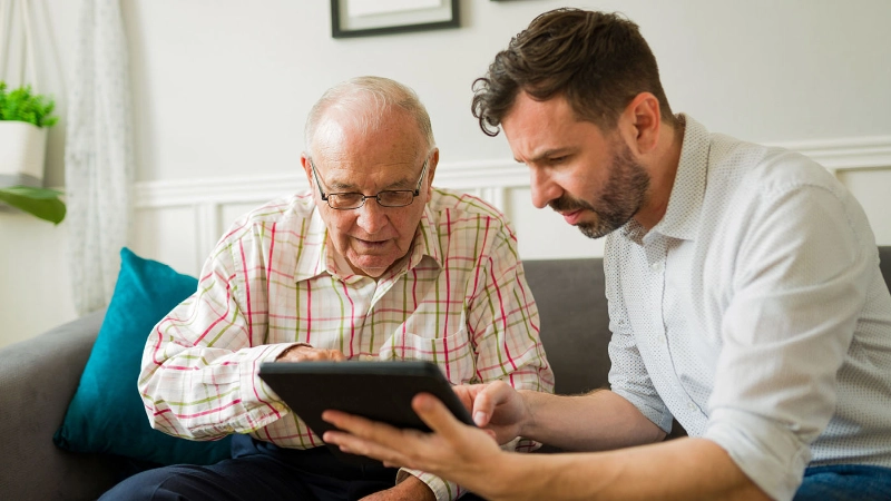 Un bénévole explique quelque chose à une personne âgée sur une tablette