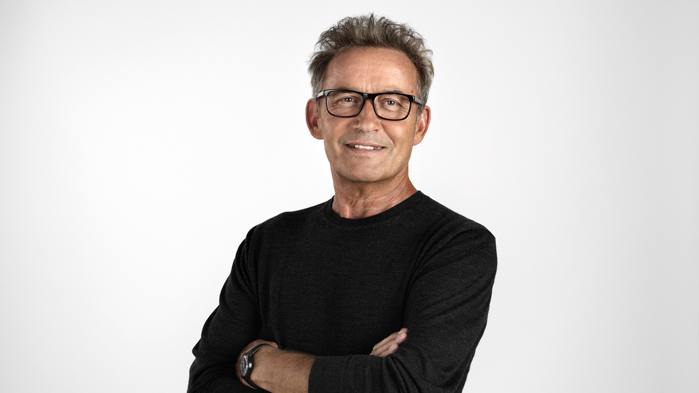 Homme âgé, bras croisés, lunettes, souriant.
